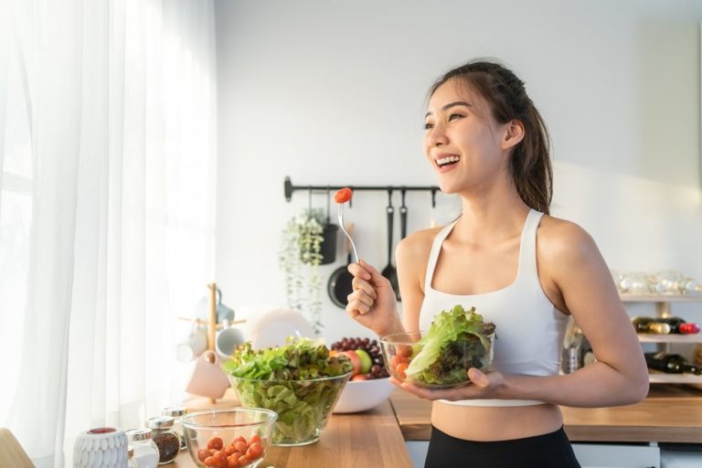 A woman smiling while eating a salad